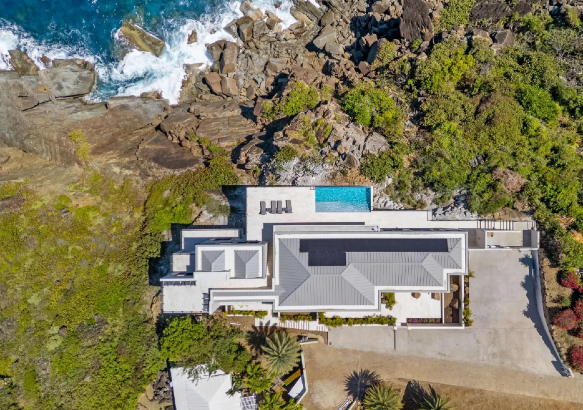 Aerial view of a completed cliffside residence beside the rocky coast